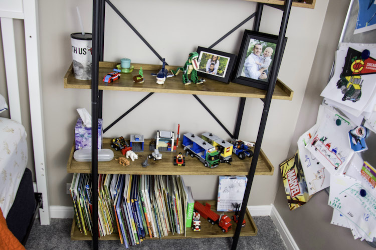Shelves in a boy's bedroom that contains books, trophies, photos, and lego sets.