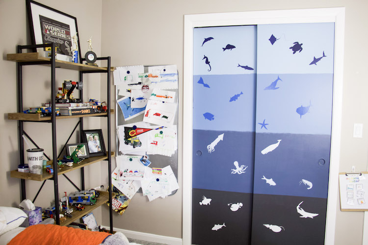 Shelves in a boy's bedroom that contains books, trophies, photos, and lego sets with a closet door in the background.