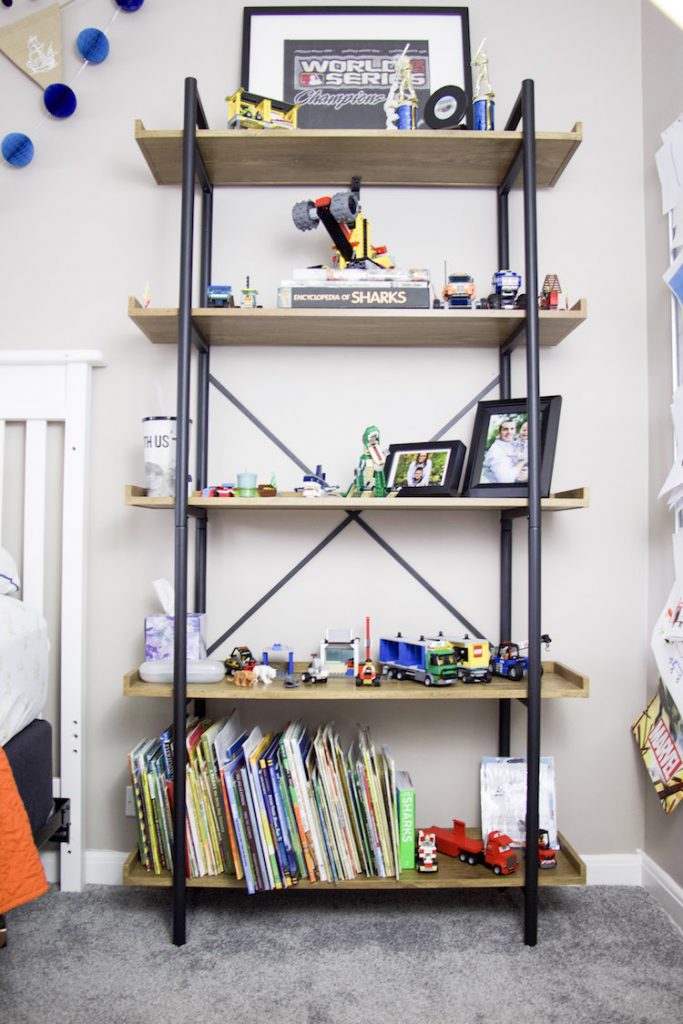 Shelves in a boy's bedroom that contains books, trophies, photos, and lego sets.