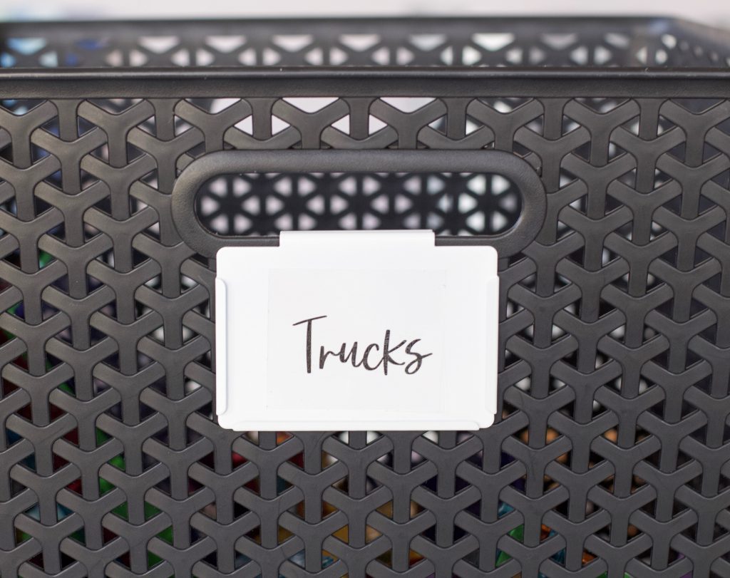 close up of cursive hand lettered printable sticker labels. black bin with white bin clip and black cursive lettering