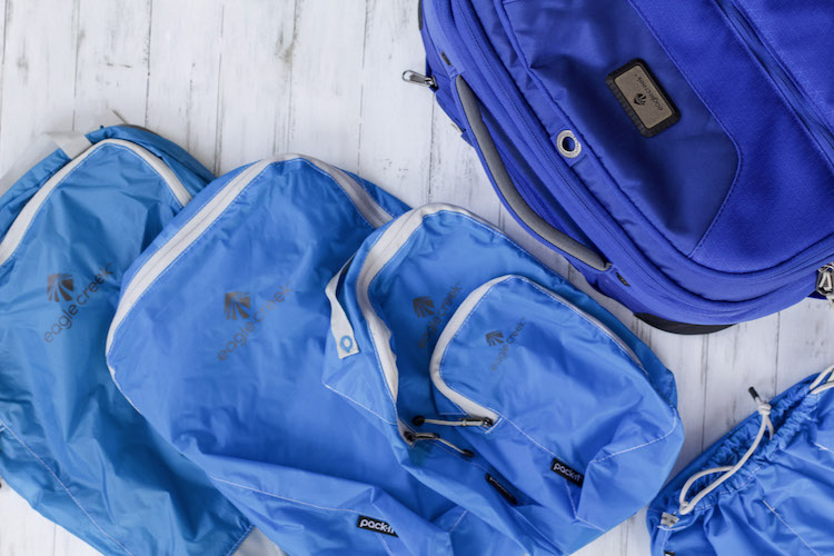 Packing cubes lying flat next to suitcase and travel packing list