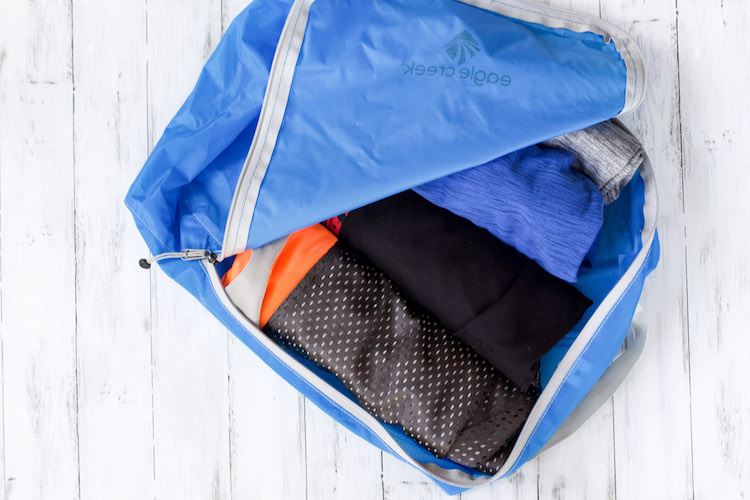 rolled up clothing in packing cubes with travel packing list