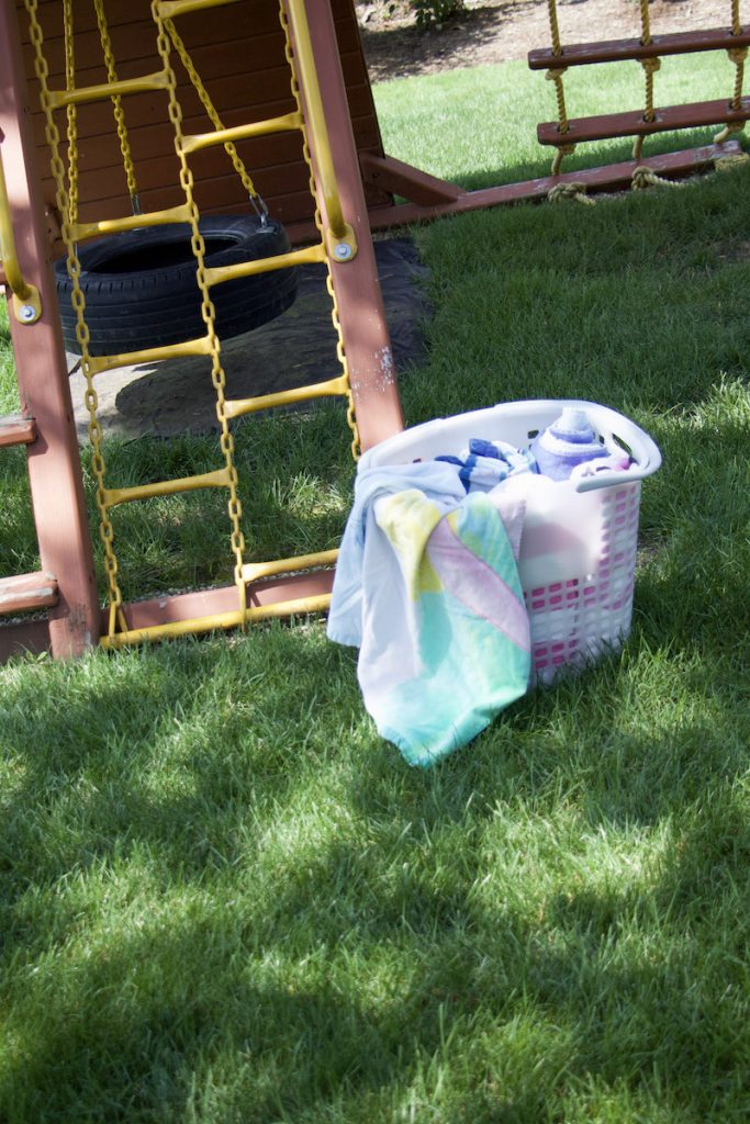 Tote outside next to playground with rolled beach towels to demonstrate towel storage ideas #beachtowels