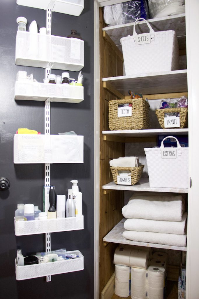 full shot of linen closet with items on door and items inside linen closet organized in bins with labels #linenclosets