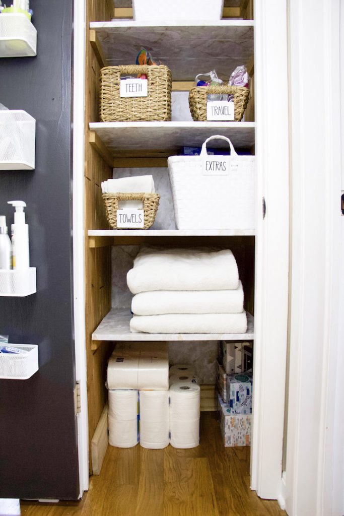 Five shelves of linen closet with marble shelf liner on all shelves and back wall of linen closet #organized
