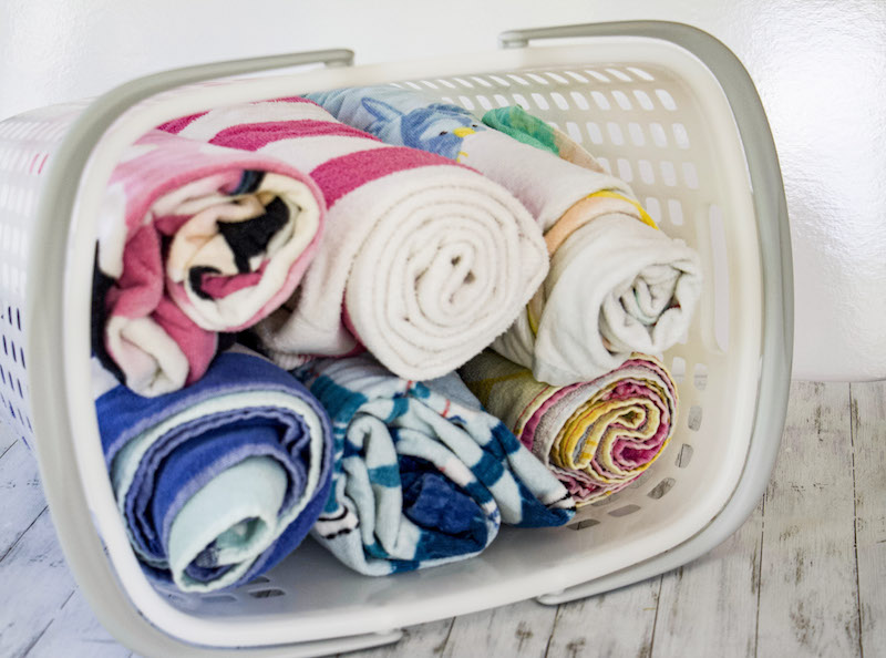 Rolled towels stored in tote from The Container Store to demonstrate towel storage ideas #beachtowels #towelstorage