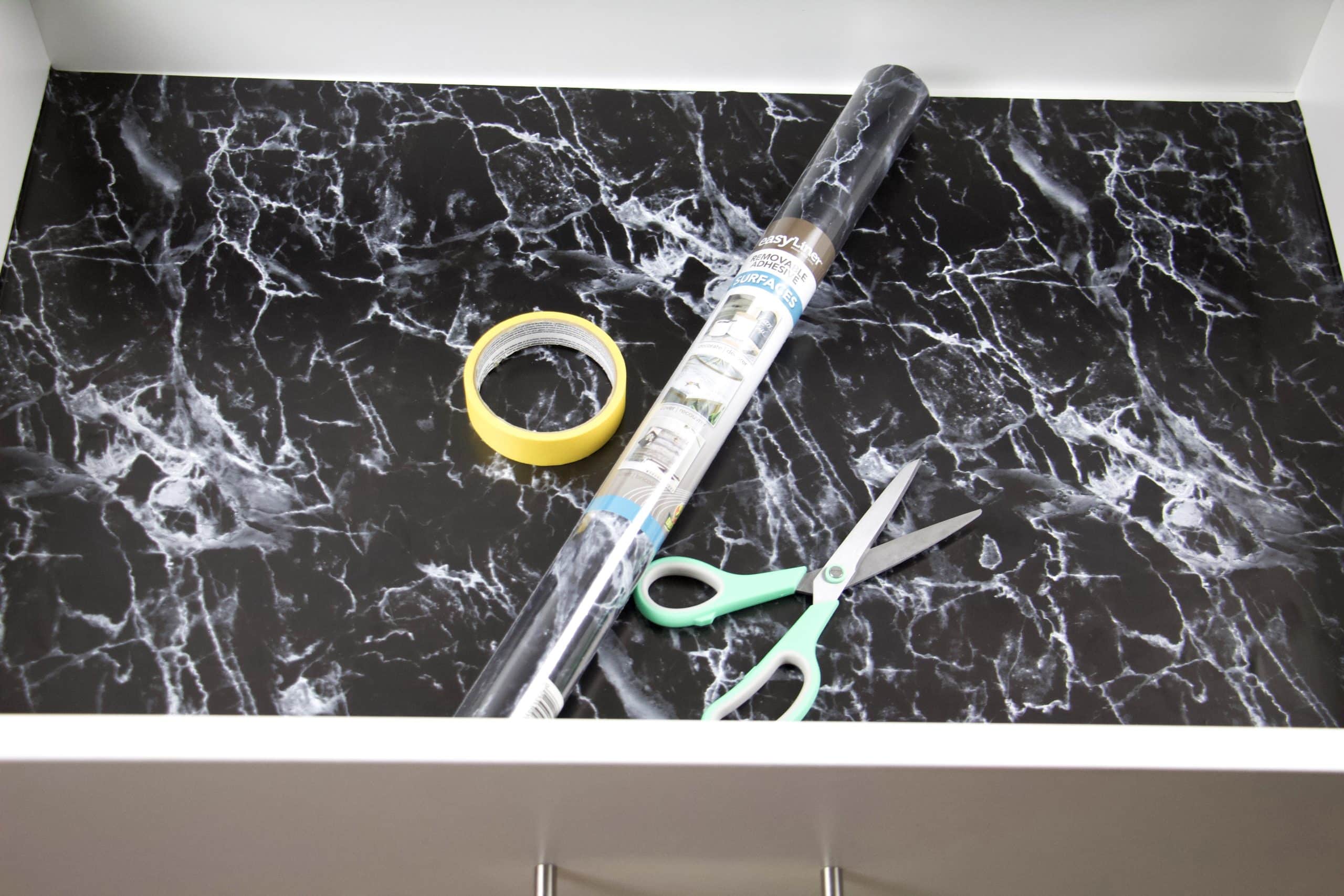 close up of drawer with black marble drawer liner and materials used including tape and scissors