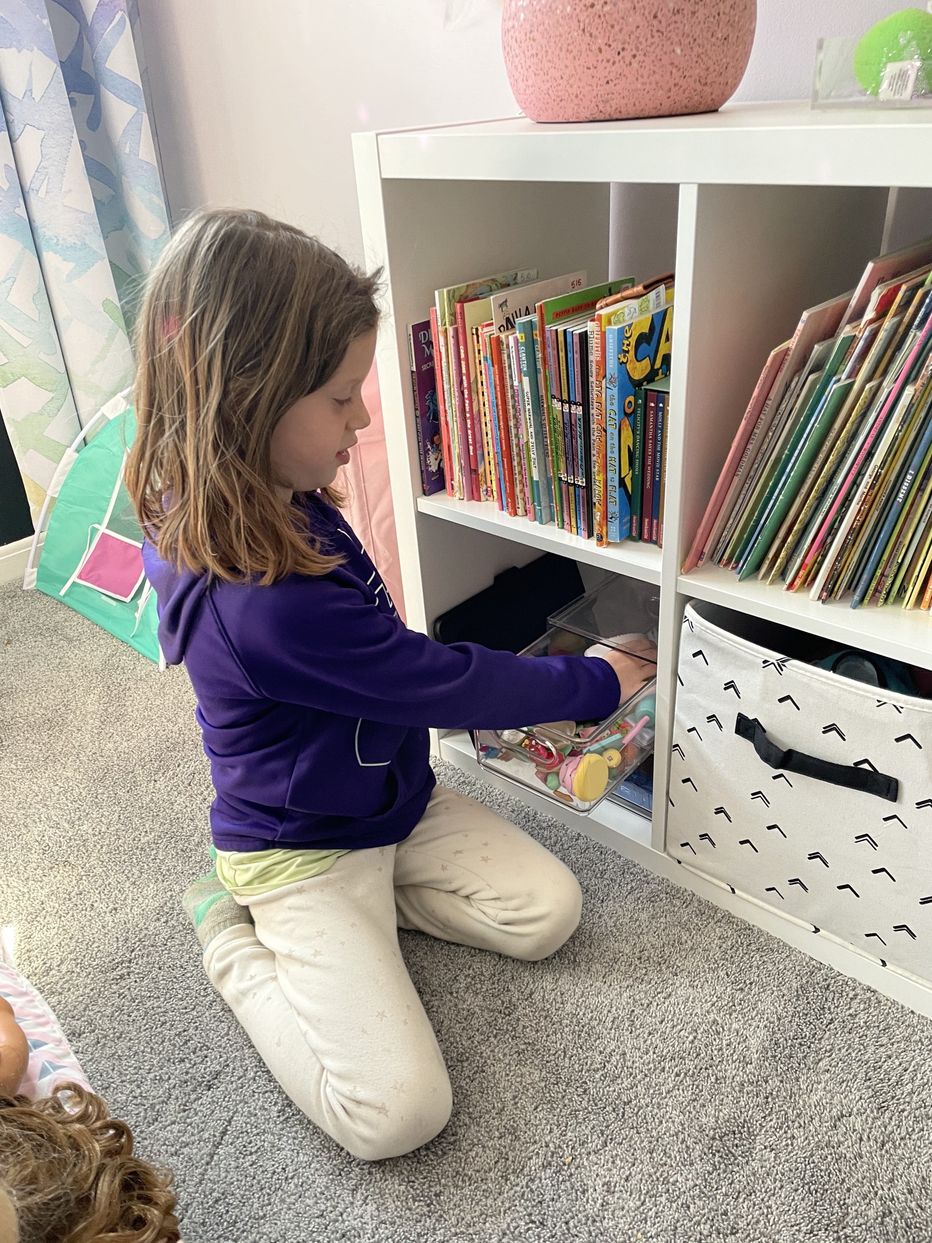 adleigh putting doll accessories into bin to keep them organized