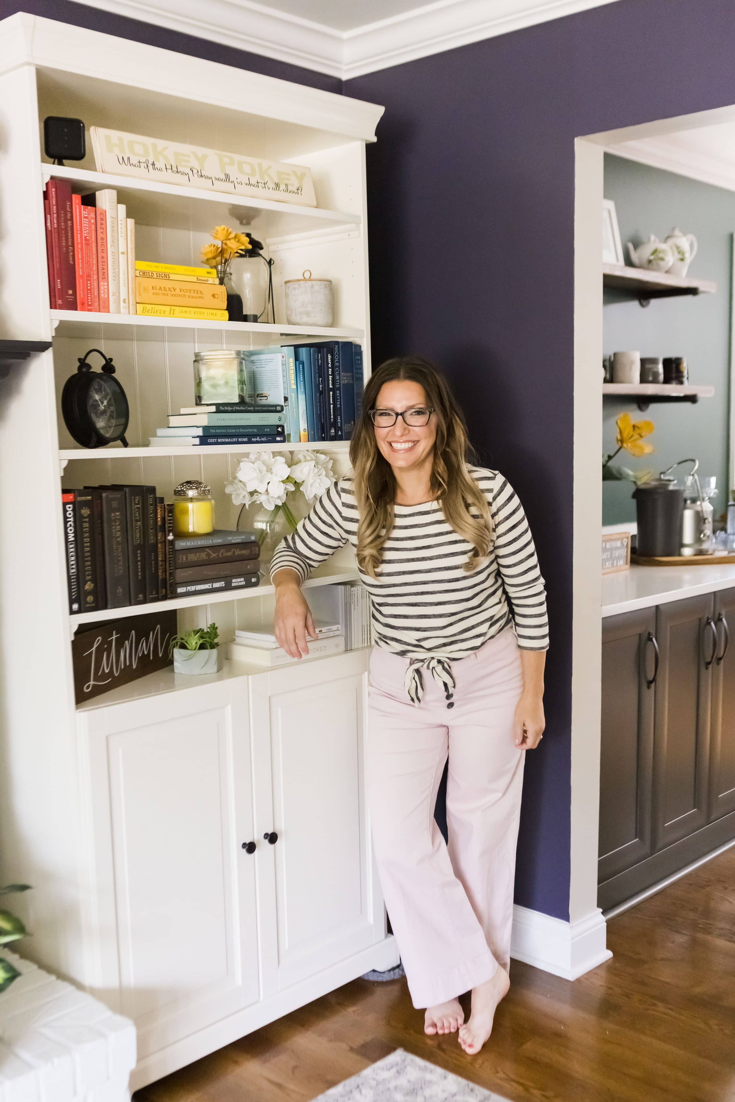 The Organized Mama leaning against bookshelf with rainbow colored books