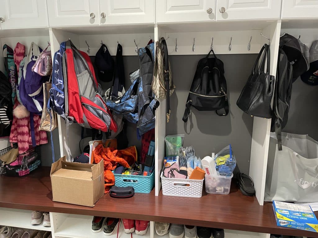 mudroom cabinets and cubbies before they were tidy with piles of things on bench and hooks