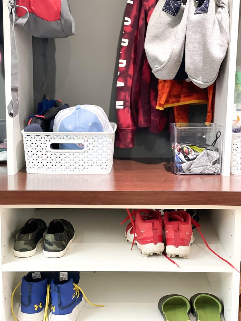mudroom shoes on shelves and bin holding hats