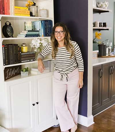 The Organized Mama leaning against bookshelf with rainbow colored books