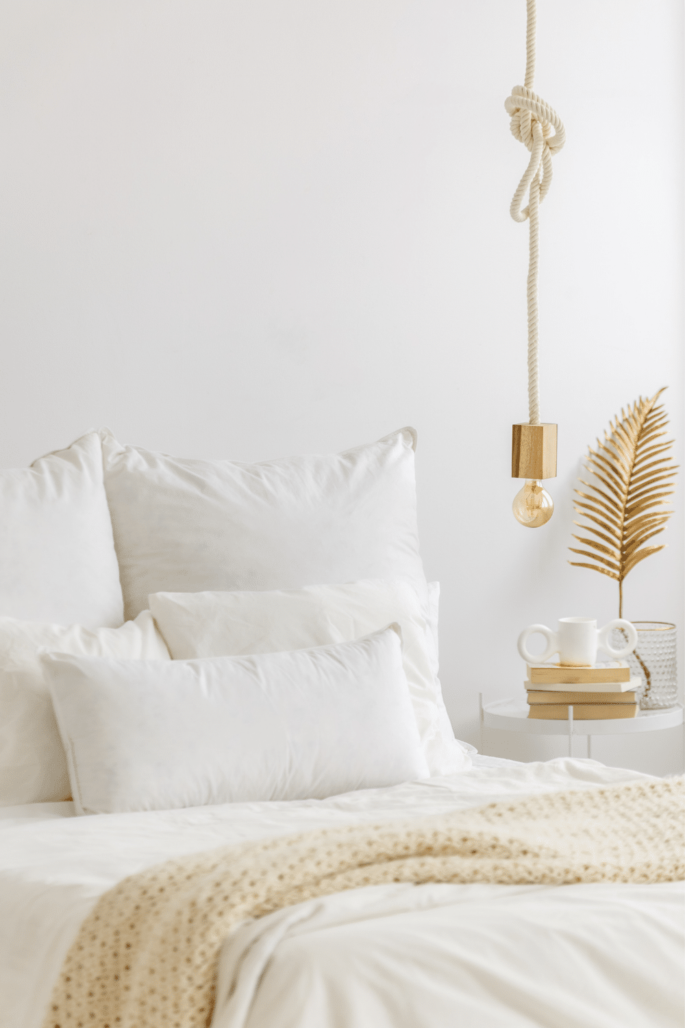 minimalist bedroom with white walls, sheets and nightstand