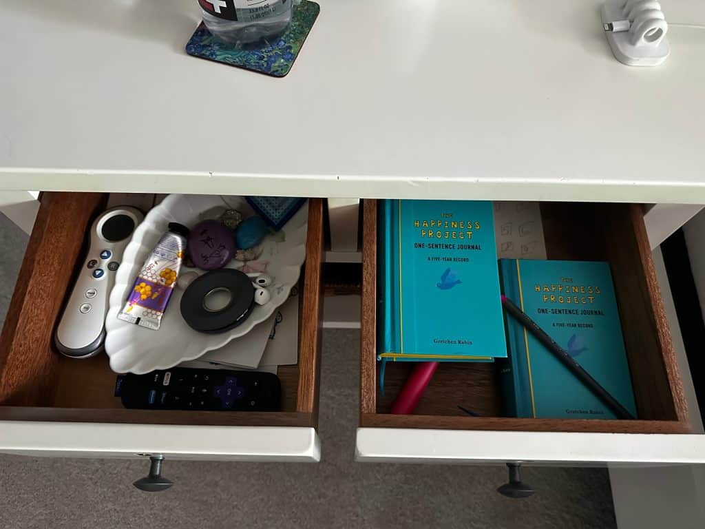 drawer nightstand in bedroom with books and remotes